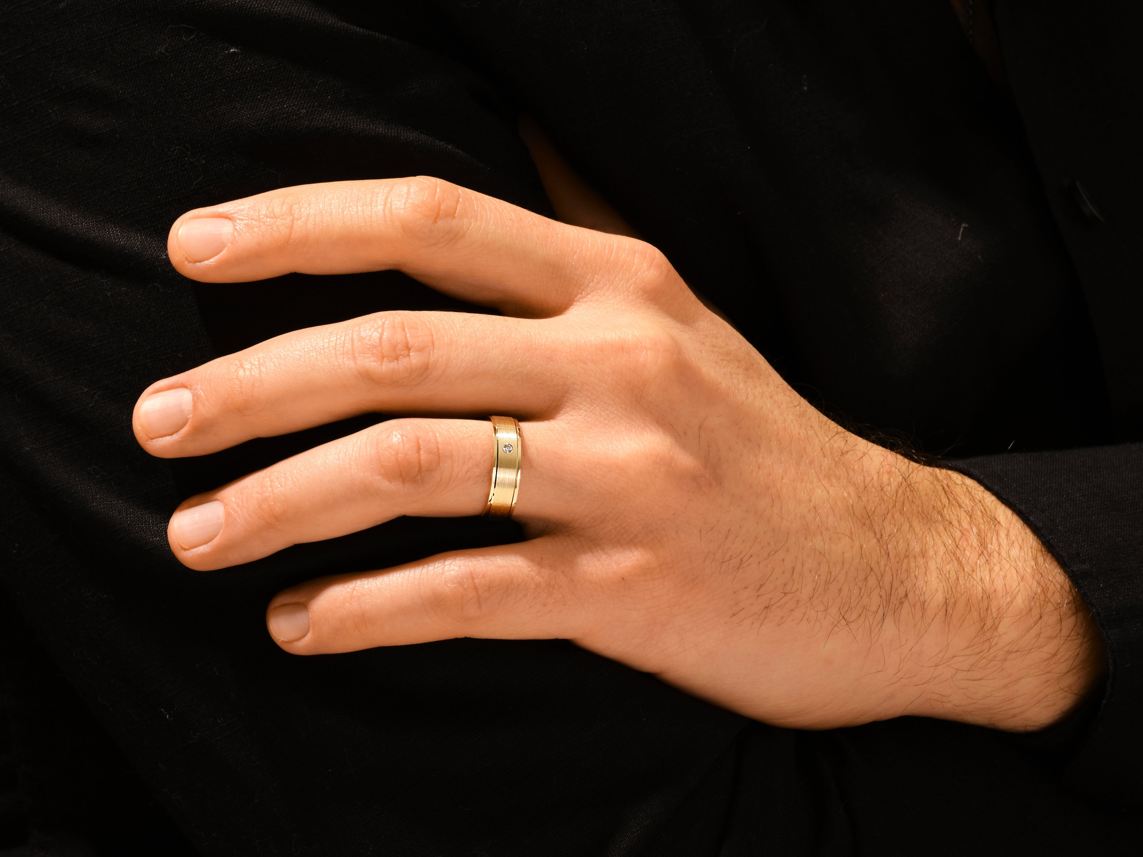 Gold wedding band with diamond on man's finger