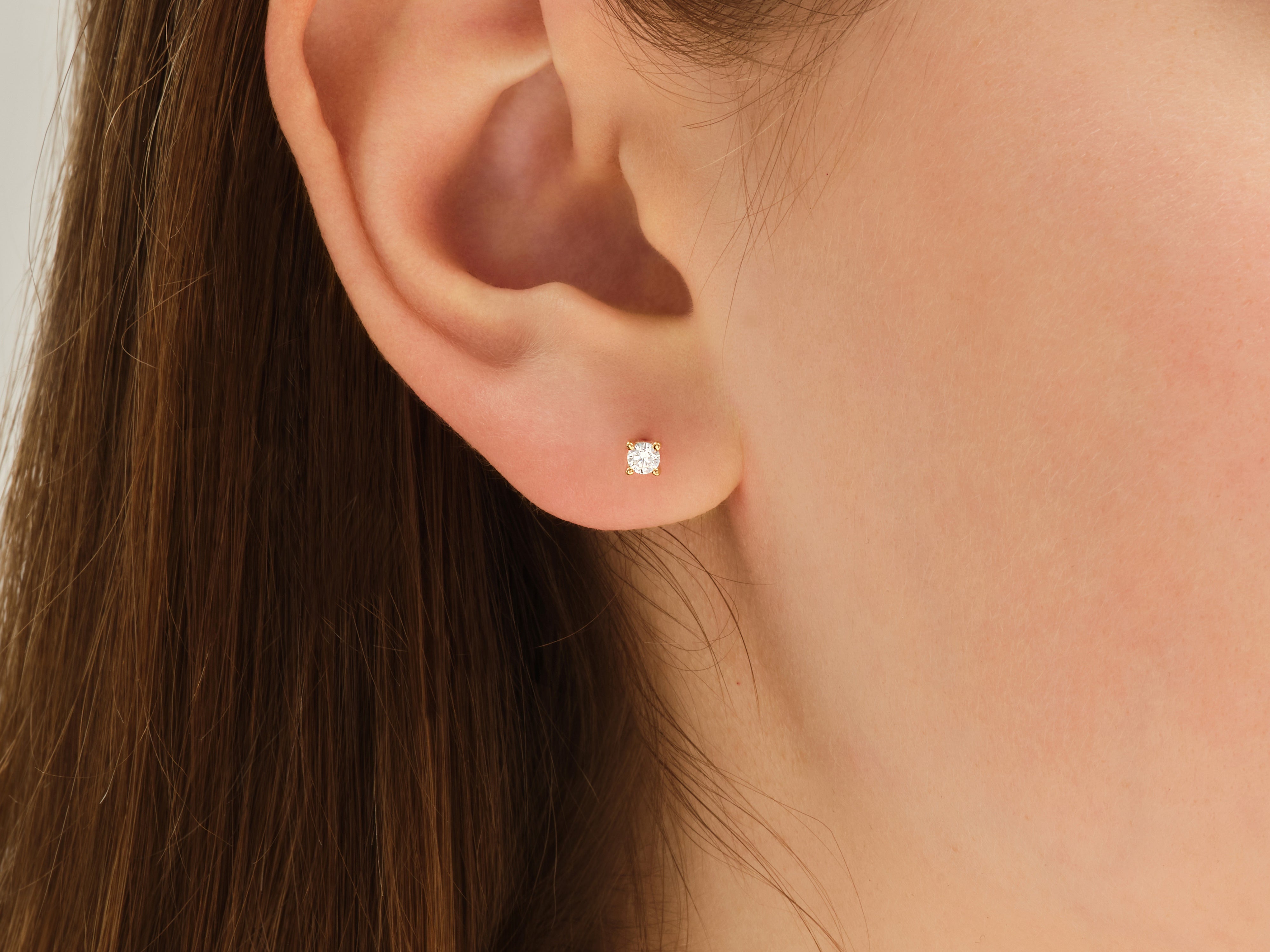 Gold diamond stud earring on a woman's ear