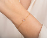Gold horseshoe charm bracelet with diamonds on a woman's wrist