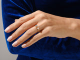 Gold ring with blue, orange, and white gems on a hand