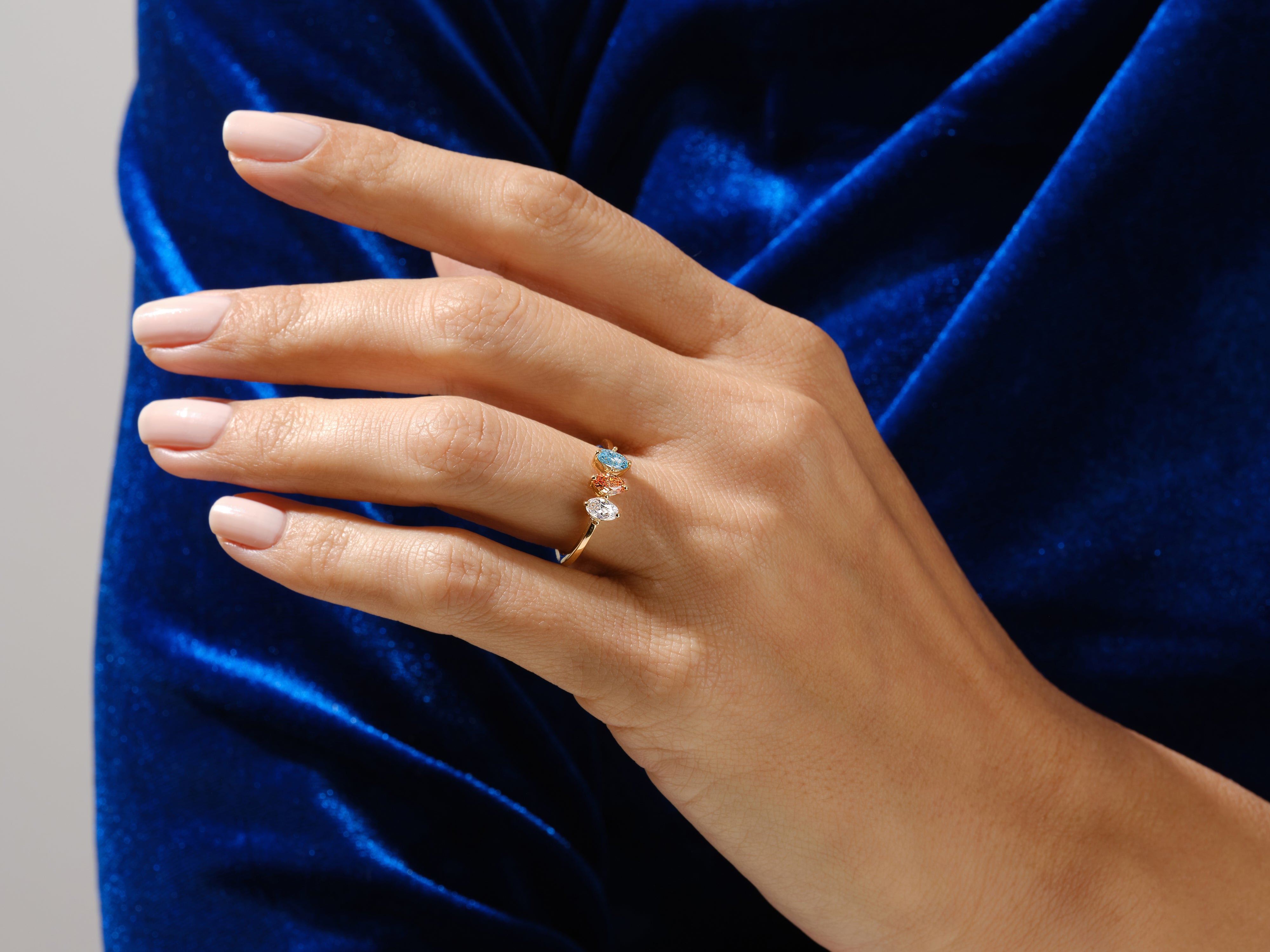 Gold ring with three colorful gemstones on a hand