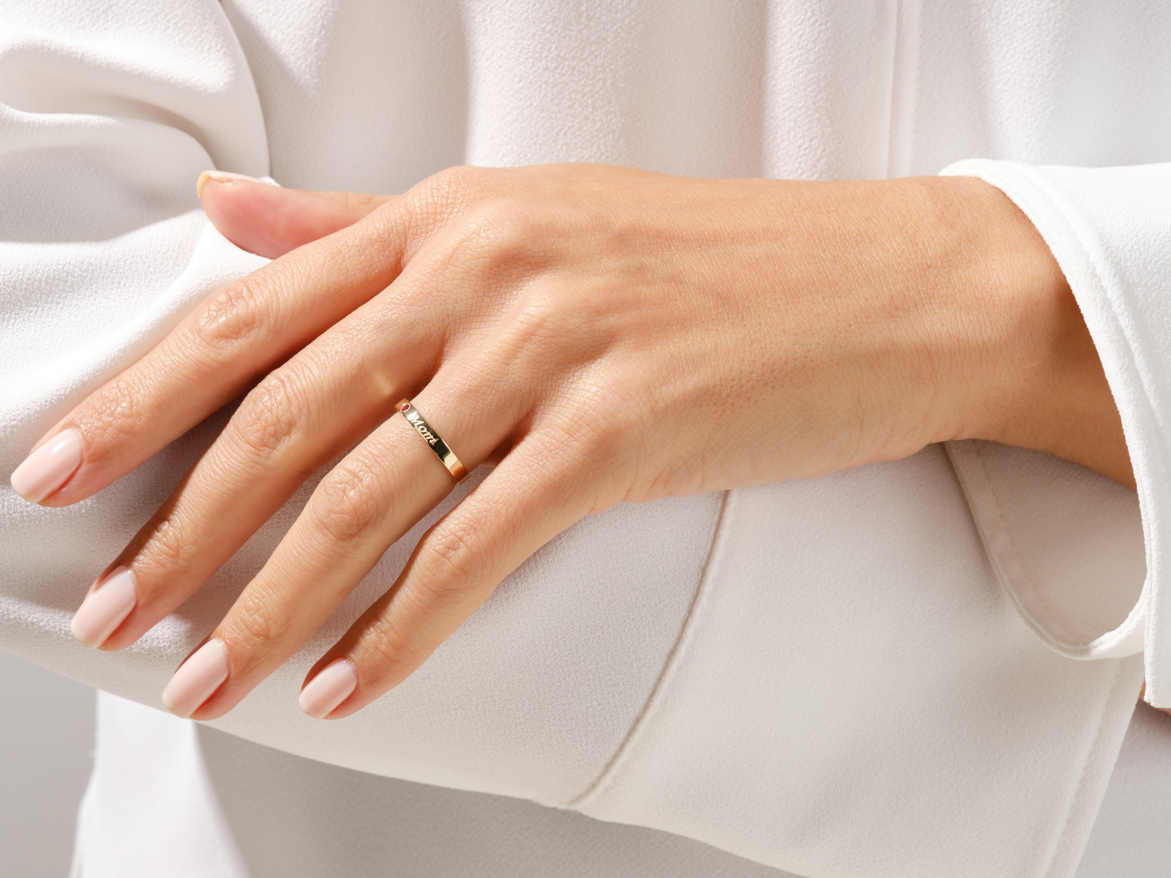 Gold ring with "Mom" engraving and ruby accent on a woman's hand