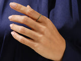 Emerald eternity band on a woman's finger, fine jewelry