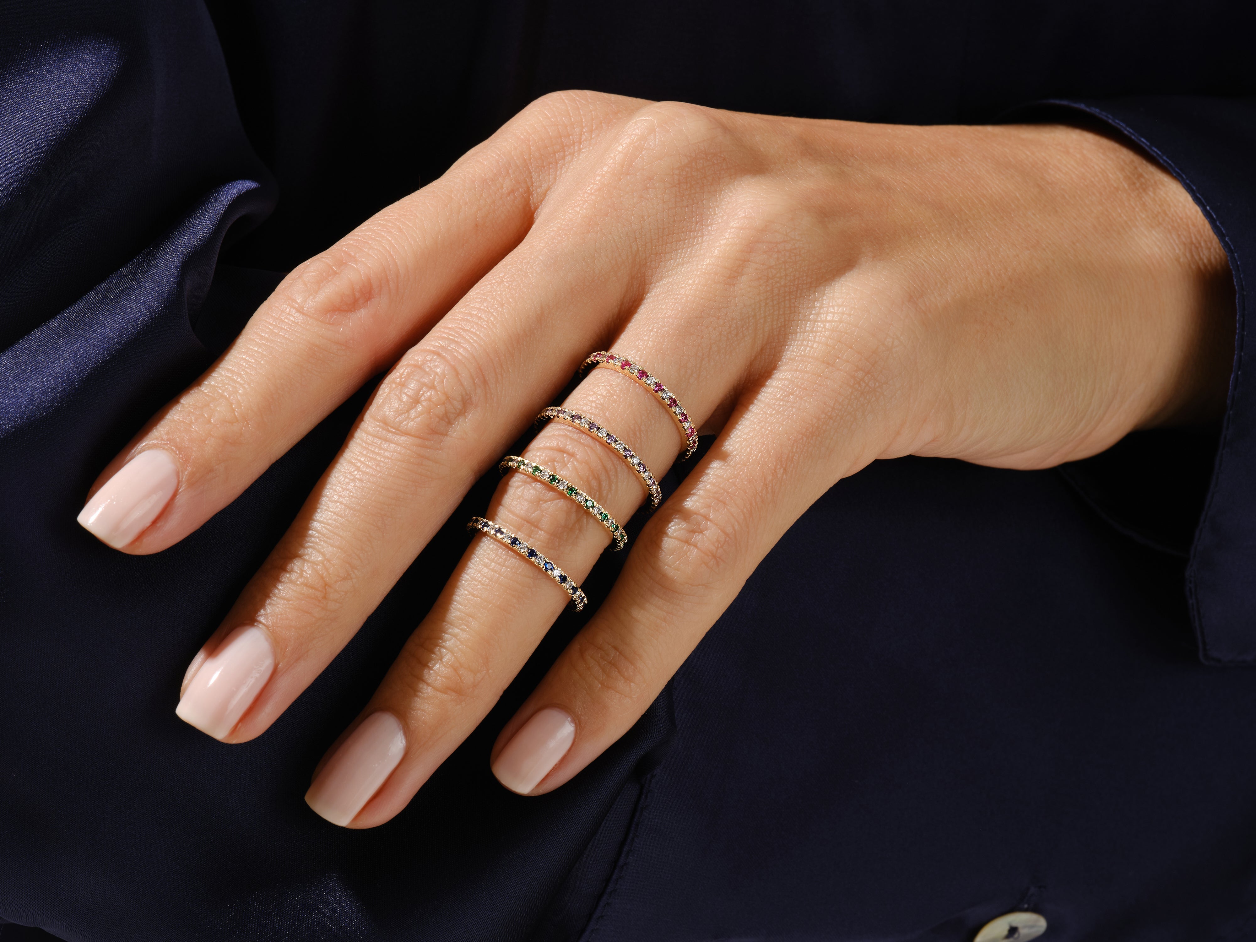 Stack of delicate gemstone eternity rings on a hand