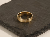 Gold ring with diamond accent on slate surface