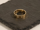 Gold band ring with diamonds on dark slate