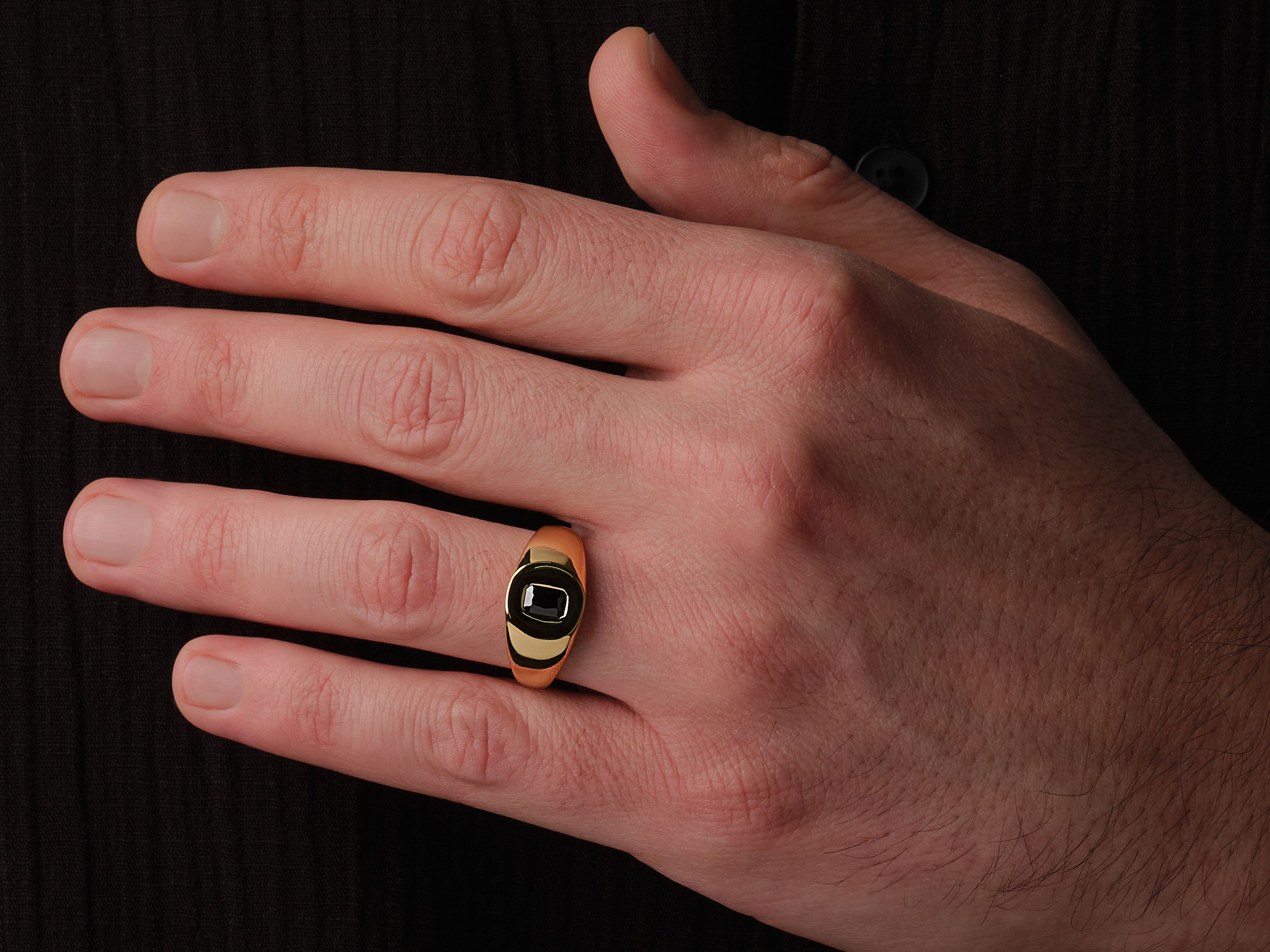 Gold ring with black stone on man's finger jewelry