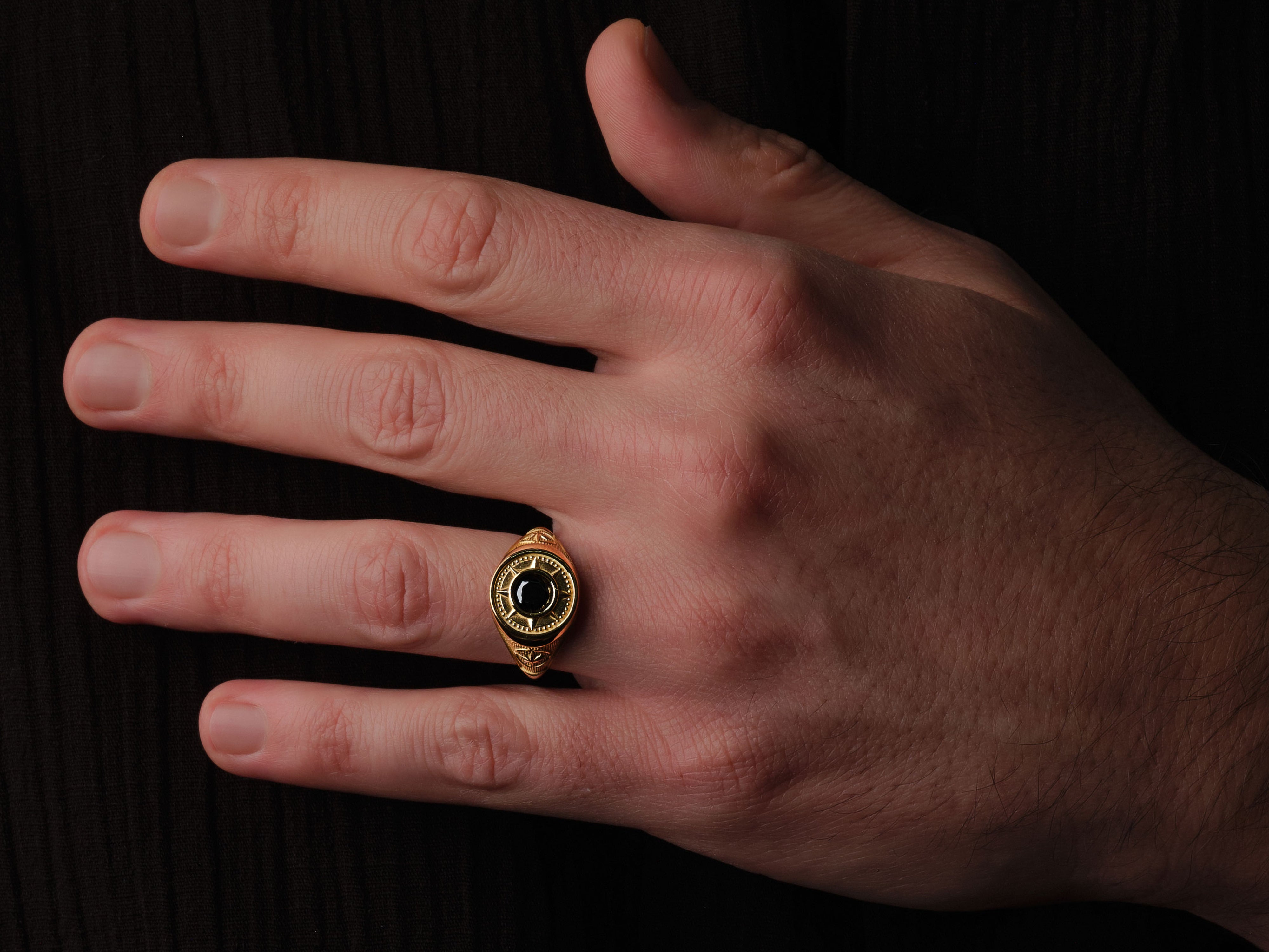 Gold ring with black stone on hand