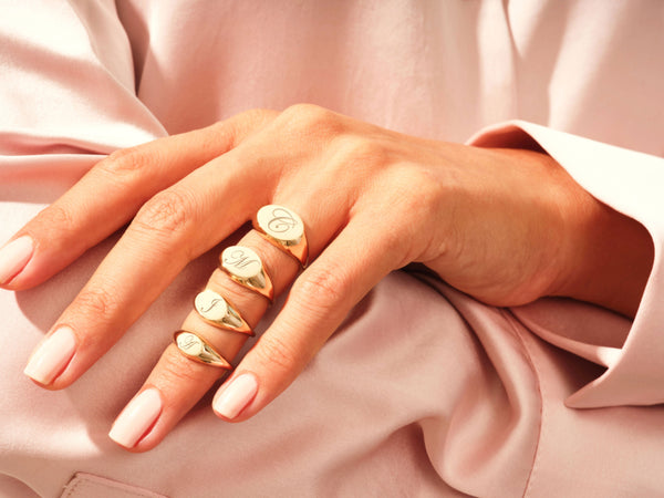 Gold initial signet rings on a hand, jewelry