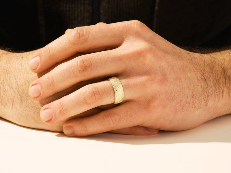 Textured gold ring on a man's finger, jewelry