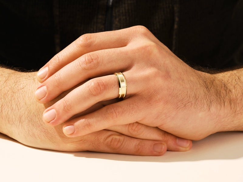 Gold wedding band on a man's finger, jewelry for men