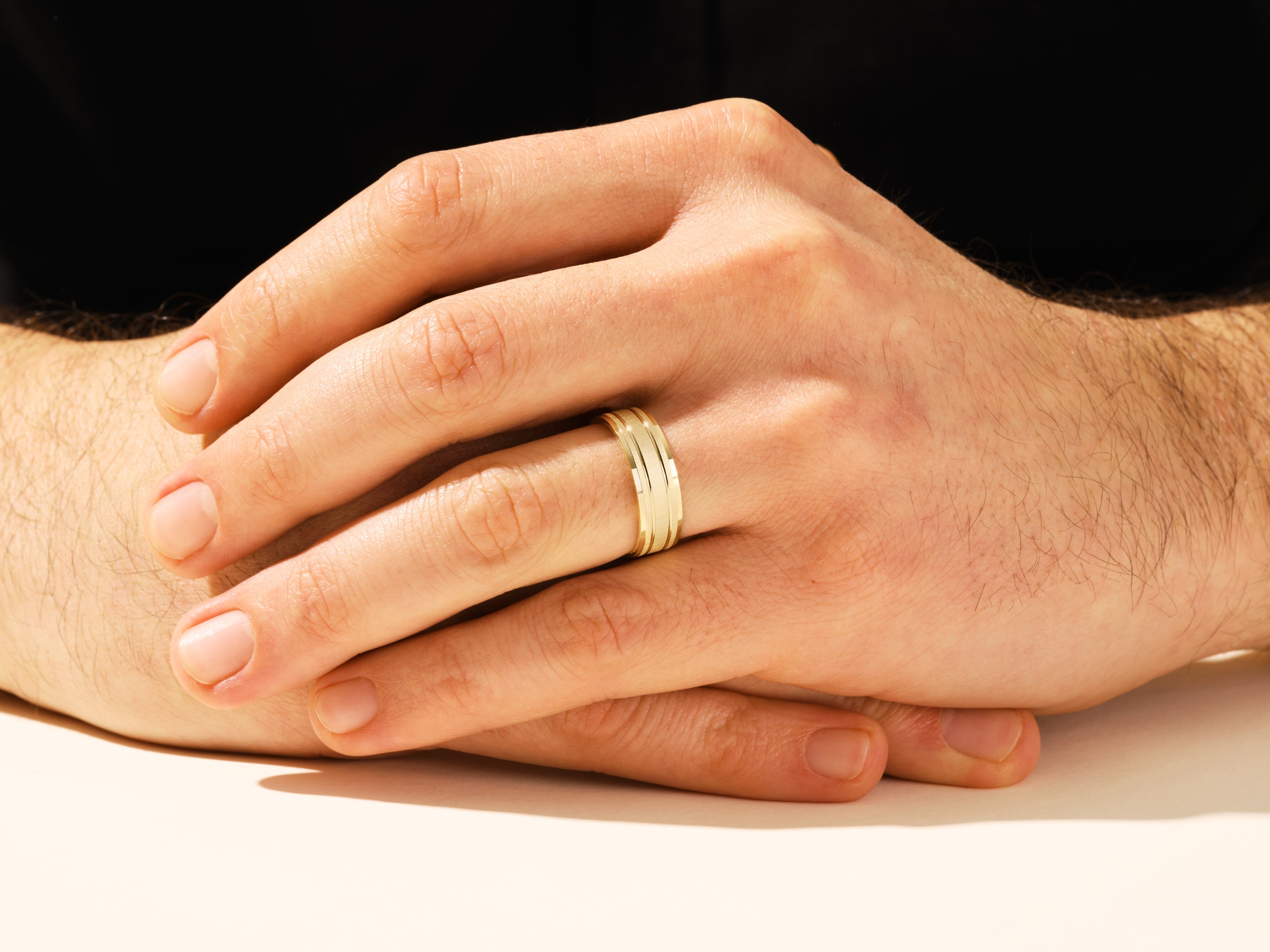 Gold wedding band on man's finger, jewelry firm product
