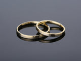 Two brushed gold wedding bands on reflective surface