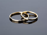 Two gold wedding bands on a reflective surface