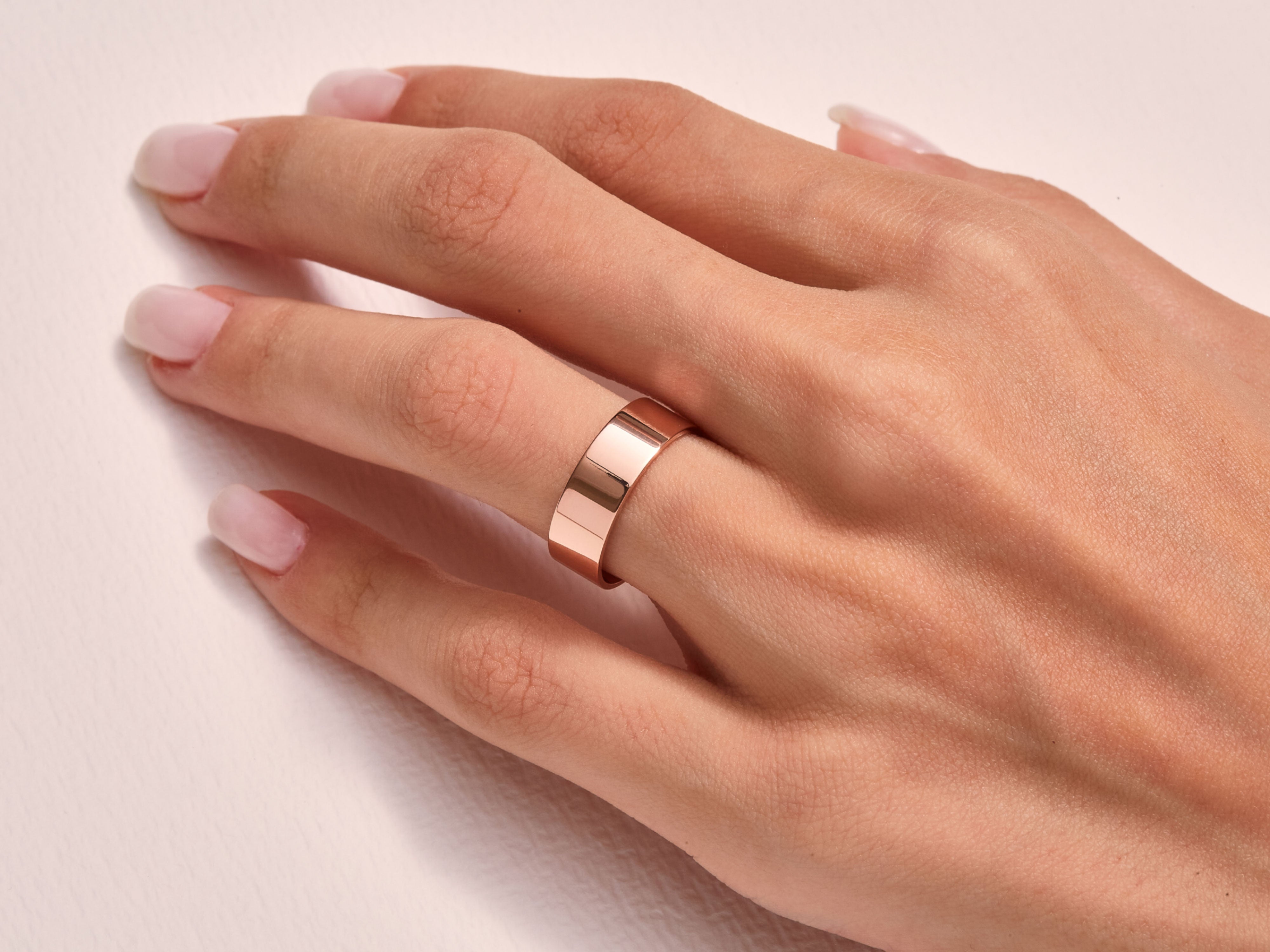 Rose gold band ring on a woman's finger, elegant jewelry