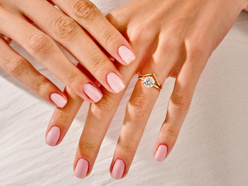 Diamond engagement ring on a hand with pink nails