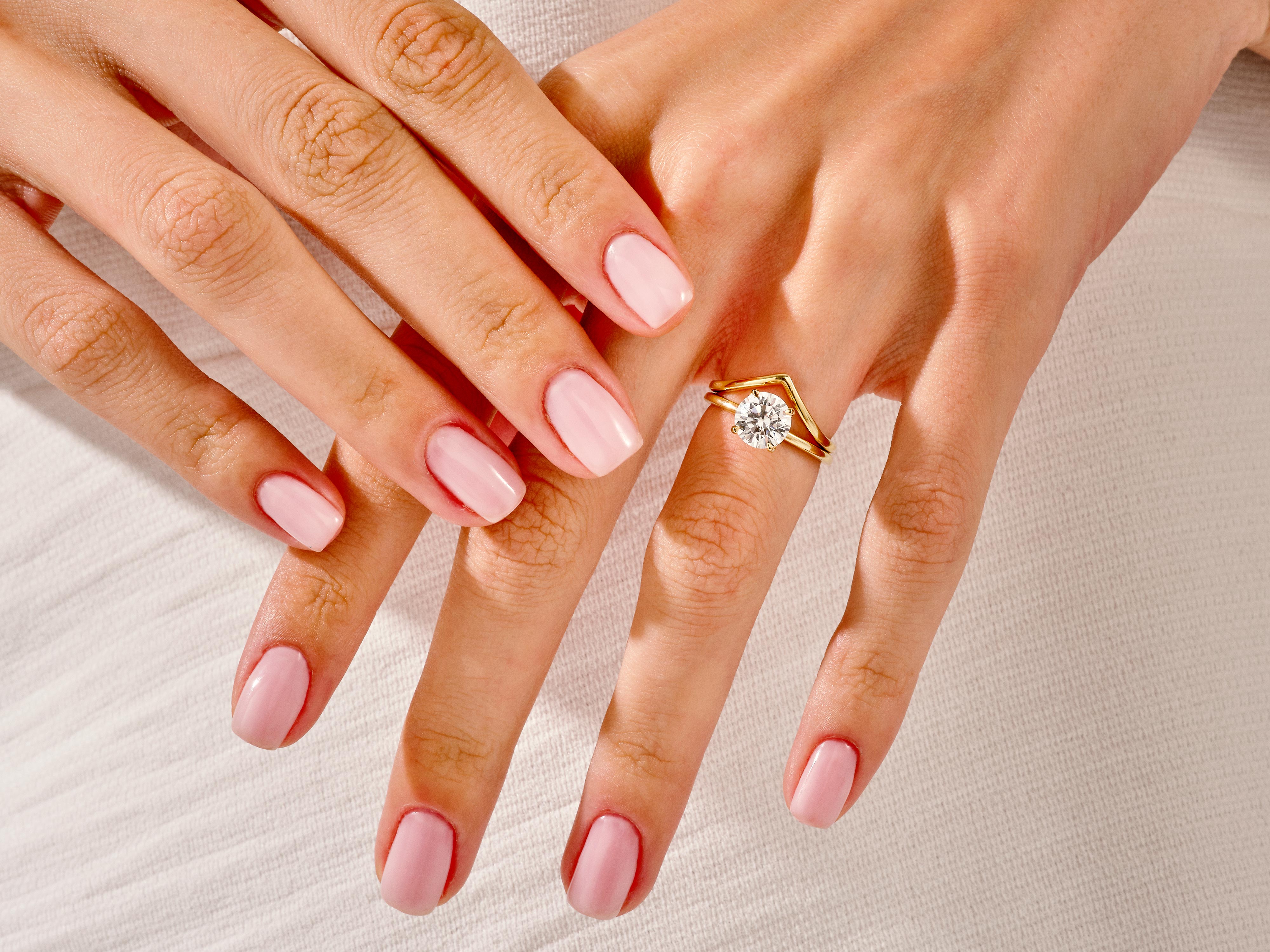 Diamond engagement ring on a hand with pink nails
