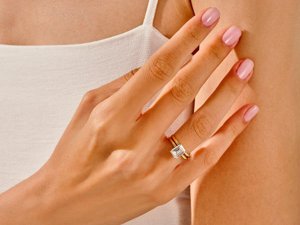 Elegant gold ring with emerald cut diamond on hand