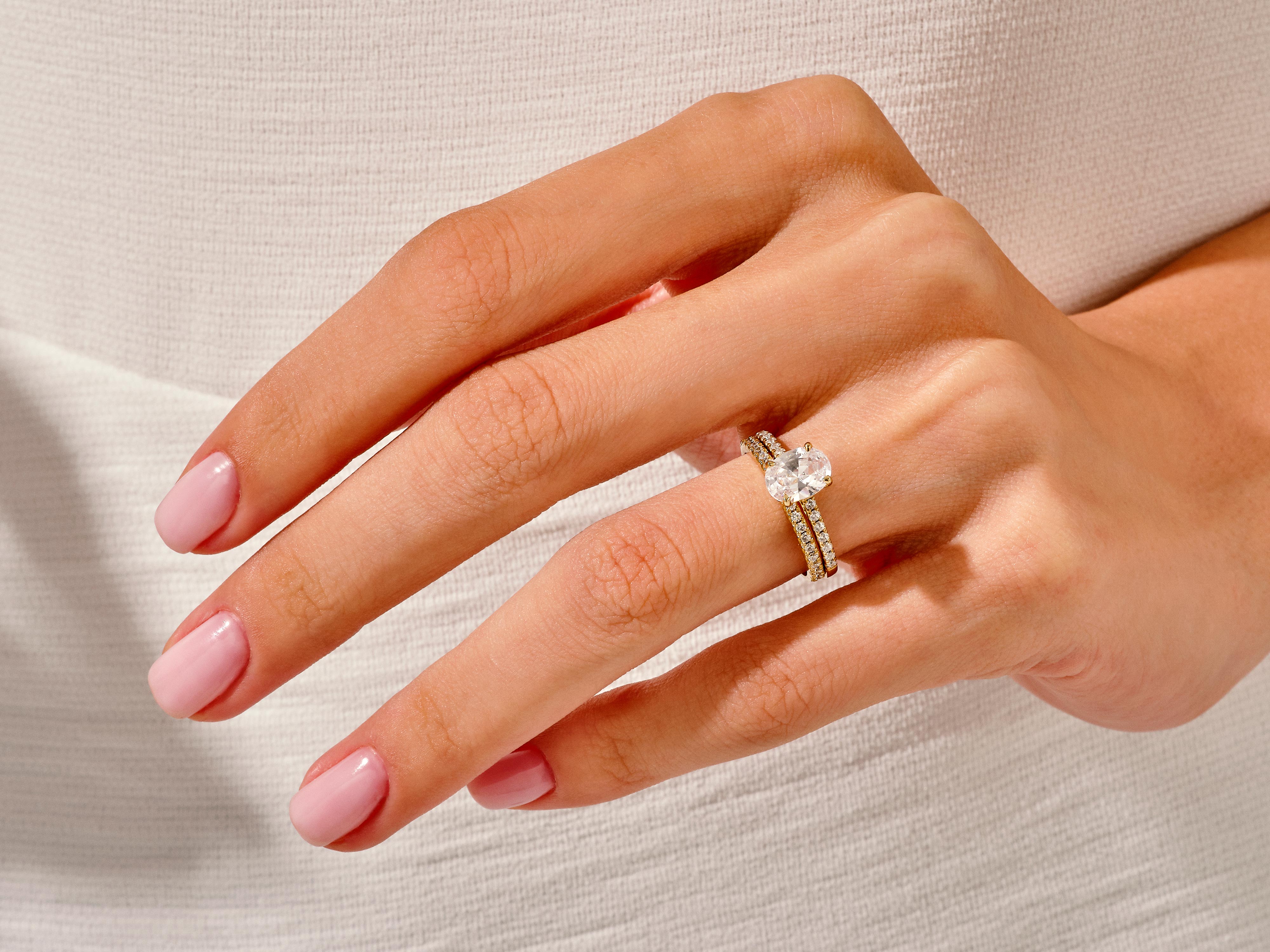 Diamond engagement ring set on a hand with pink nails
