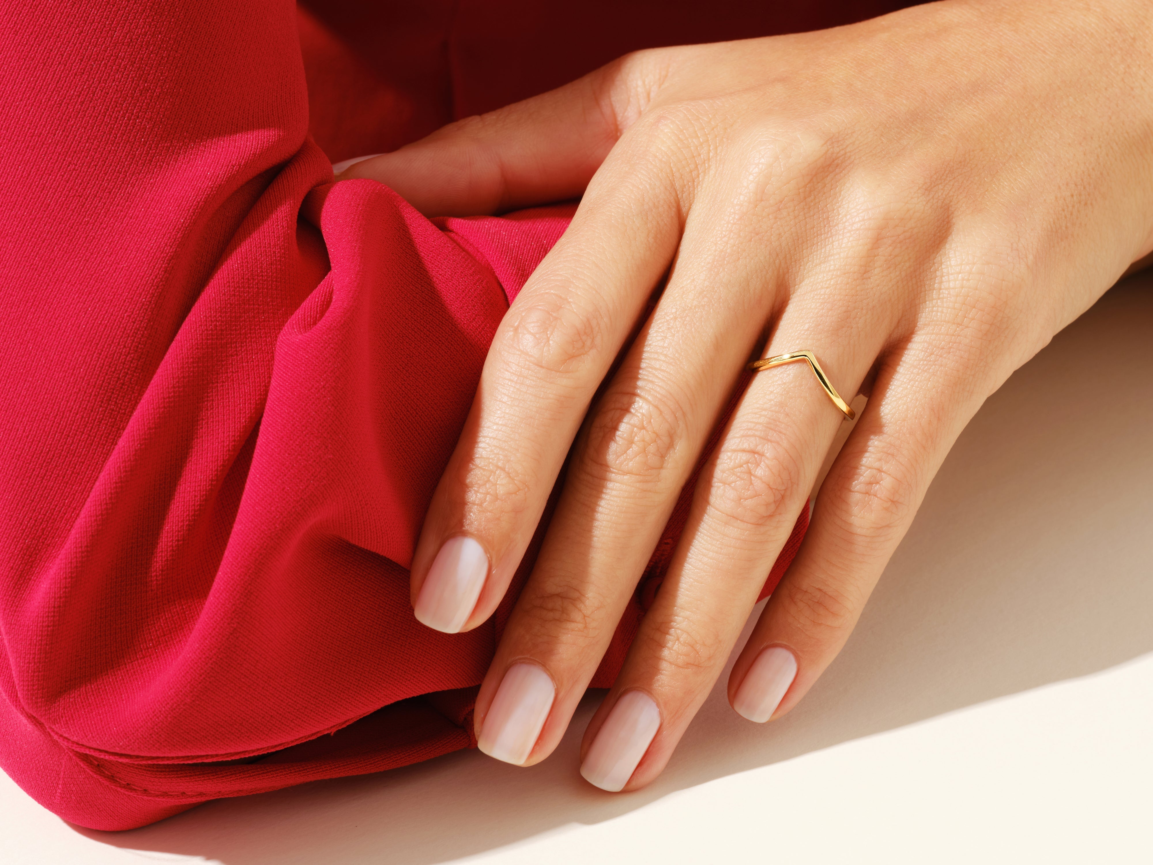 Gold chevron ring on hand with red fabric jewelry photography