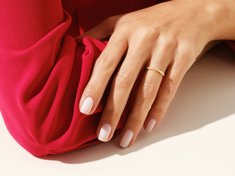 Elegant diamond ring on hand, red fabric background, jewelry