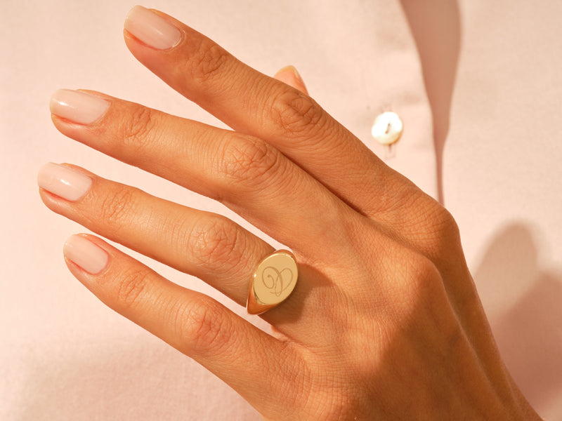 Gold heart signet ring on a woman's finger, fine jewelry