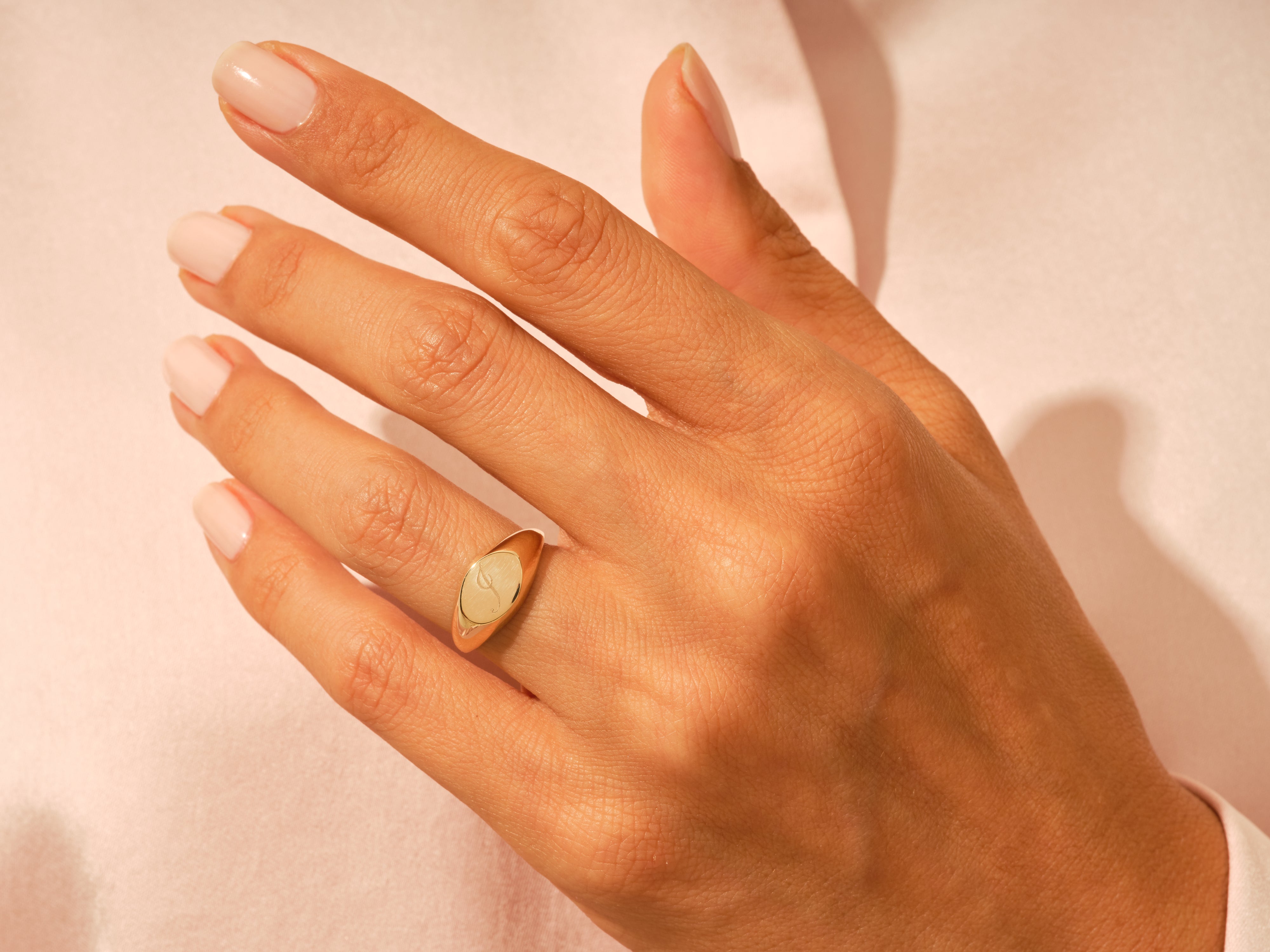 Gold signet ring with engraved initial on a woman's hand