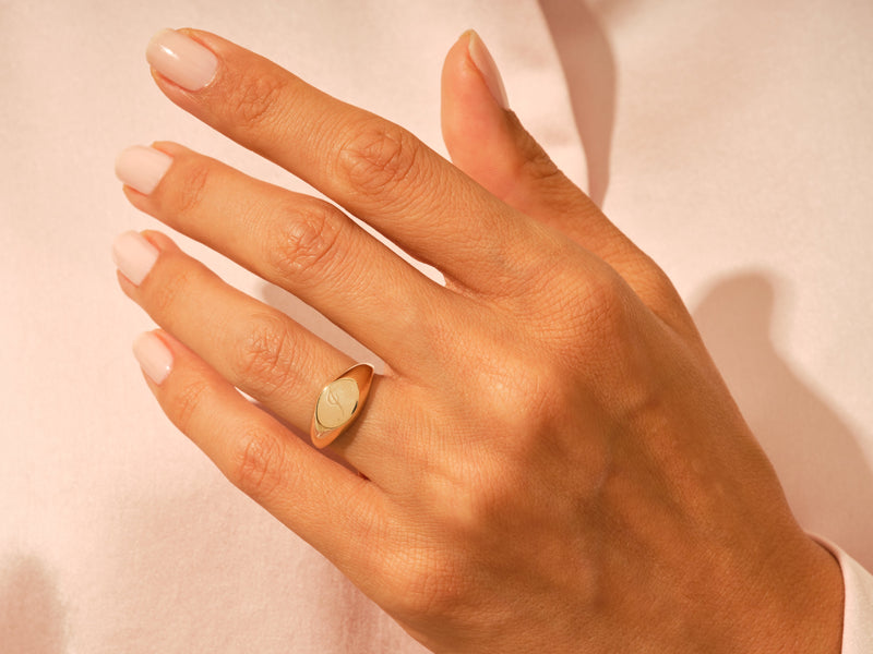 Gold signet ring with engraved initial on a woman's hand