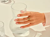 Gold snake ring on hand near elegant glassware