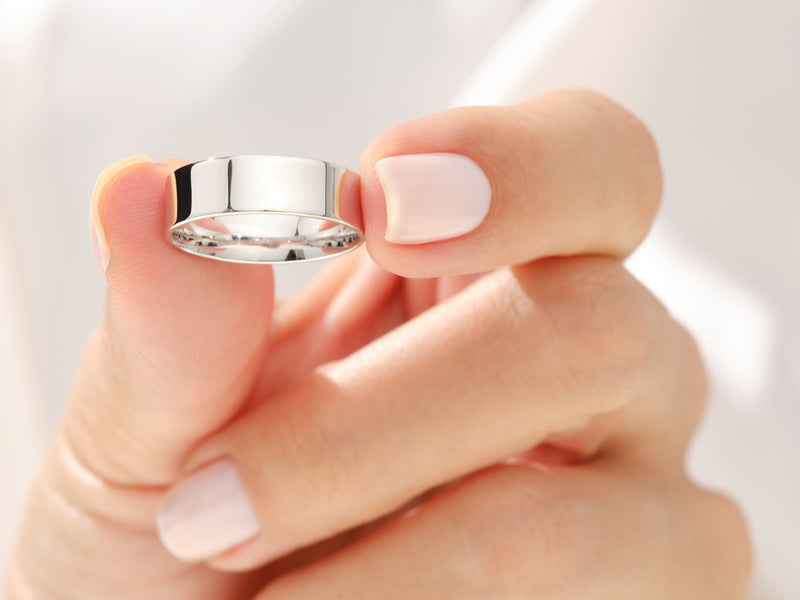 Elegant silver ring held by a manicured hand, jewelry product