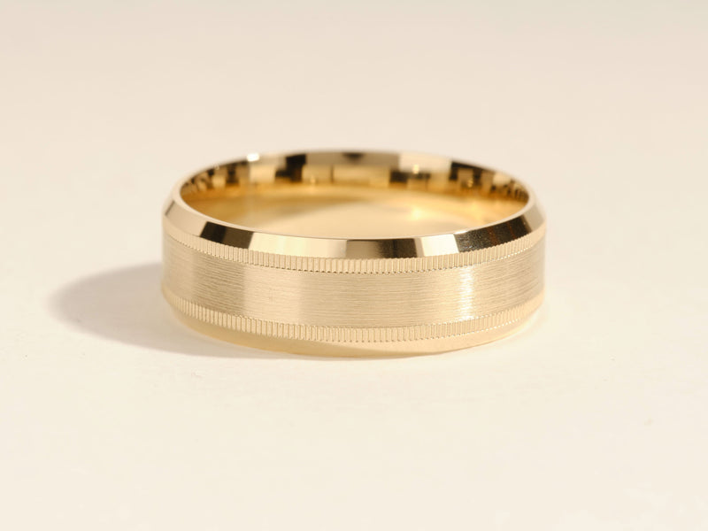 Gold wedding band with brushed finish and textured edges