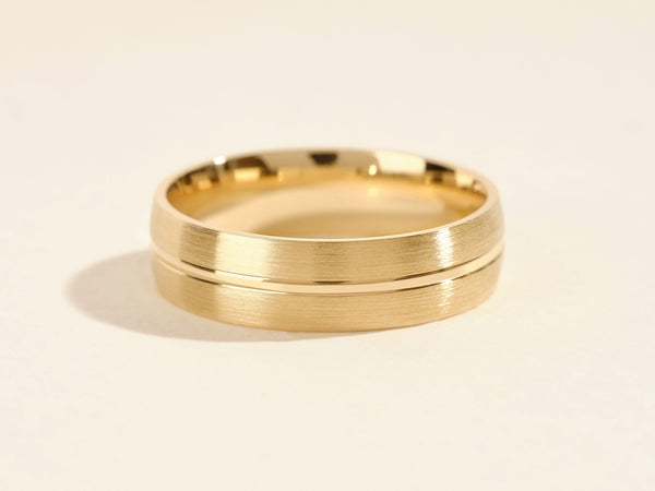 Gold wedding band with brushed finish and polished groove detail