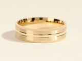 Gold wedding band with textured edges and a polished center groove