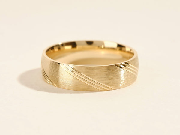 Gold wedding band with brushed finish and diagonal line detail