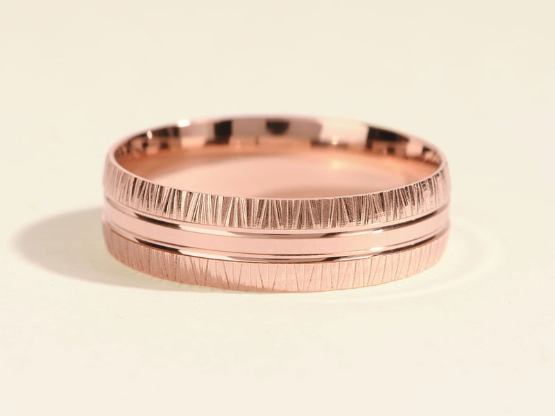 Rose gold ring with textured band and polished center detail