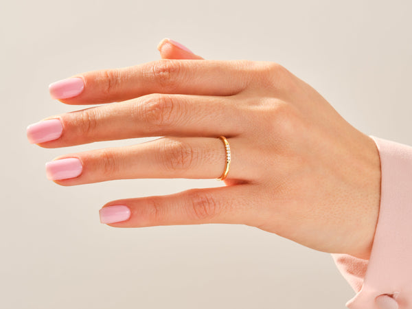 Delicate gold ring with diamonds on a manicured hand