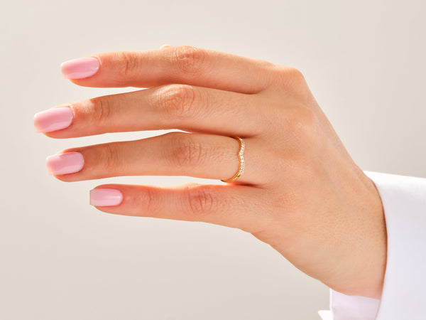 Gold diamond curved ring on a manicured hand