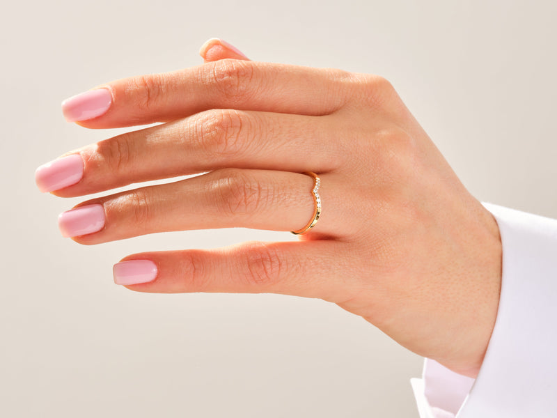 Gold diamond curved ring on a woman's finger