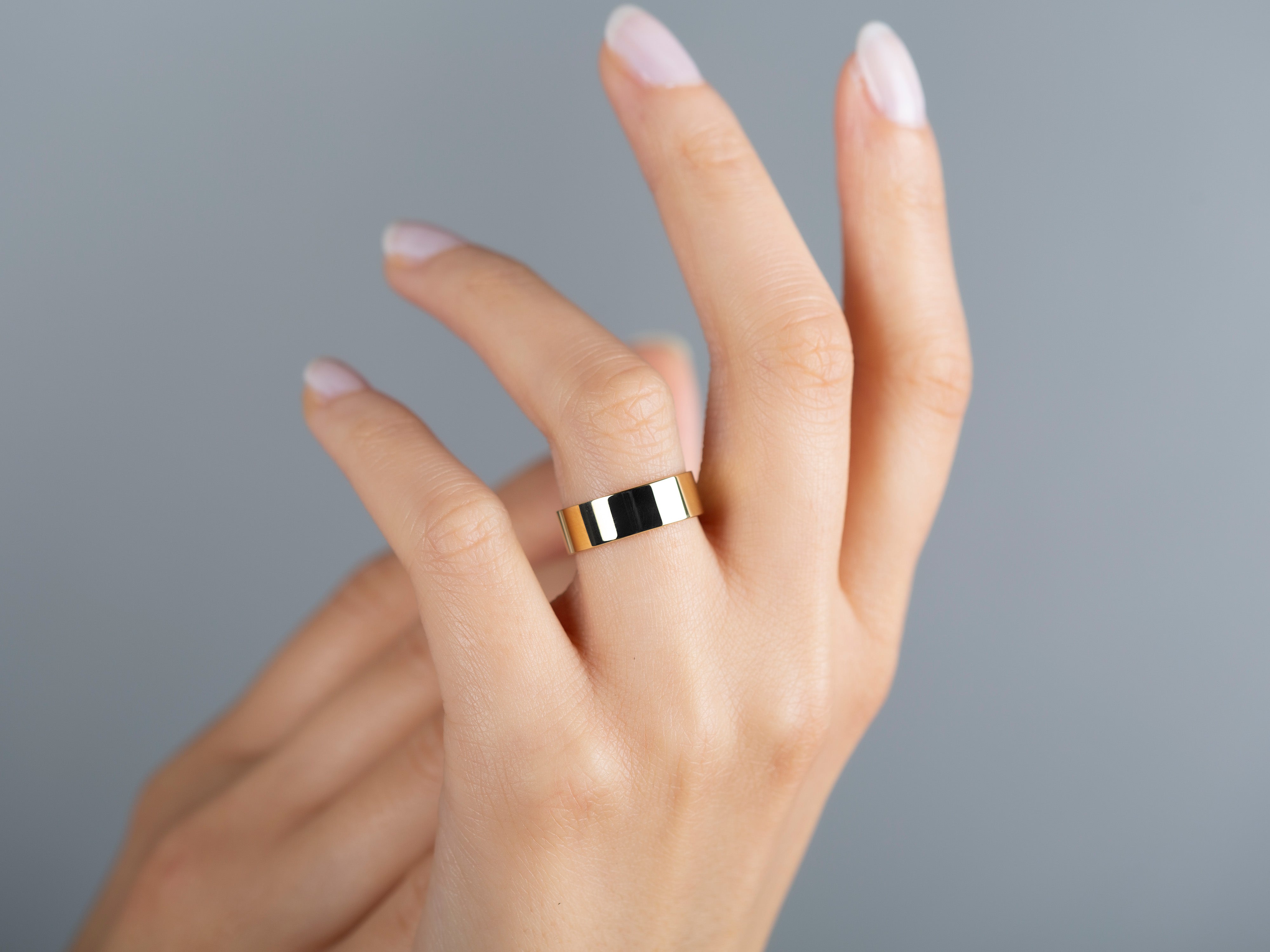 Gold band ring on a woman's finger, elegant jewelry for sale