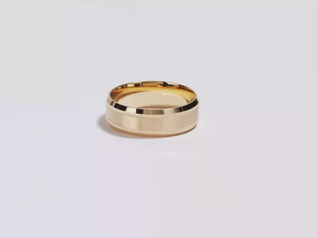 A video showing a yellow gold 7mm milgrain and beveled edge men's wedding band spinning on a white background.