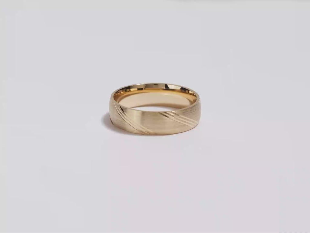 A video showing a yellow gold 6mm diagonal lined men's gold wedding band spinning on a white background.