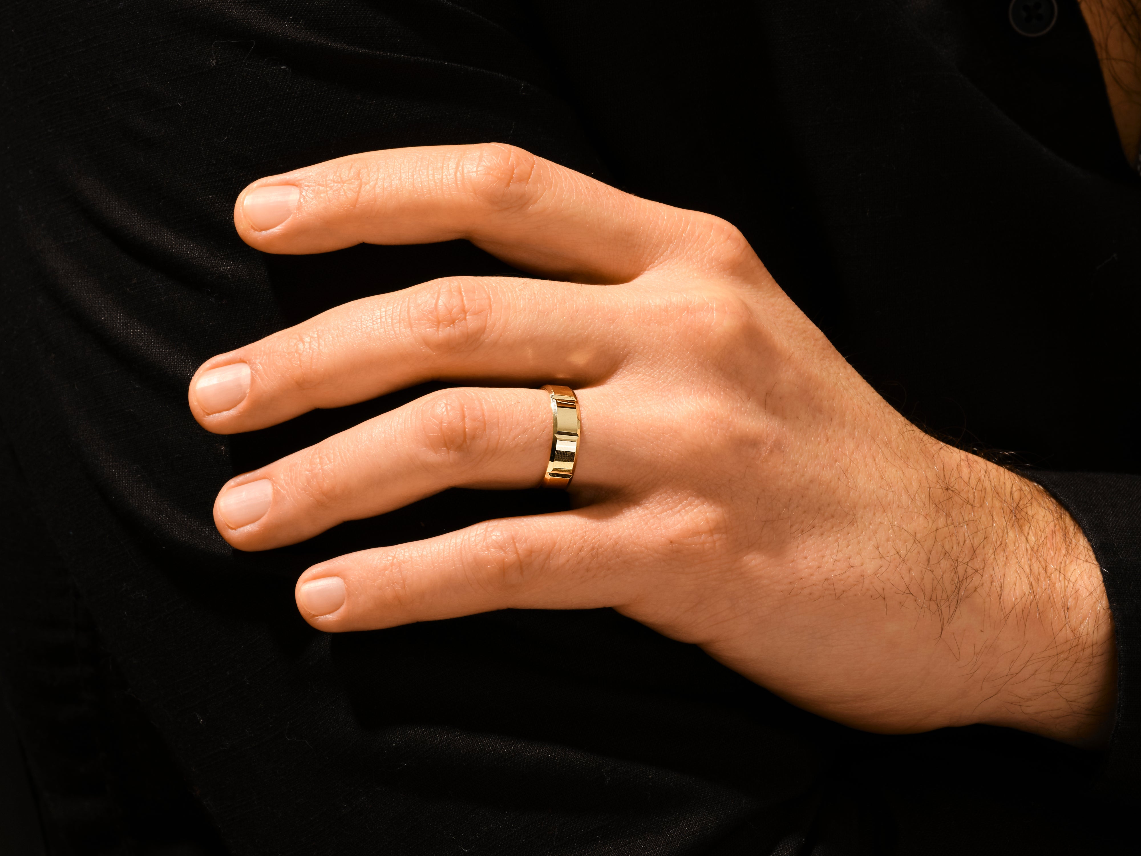 Gold band ring on a man's finger, luxury jewelry