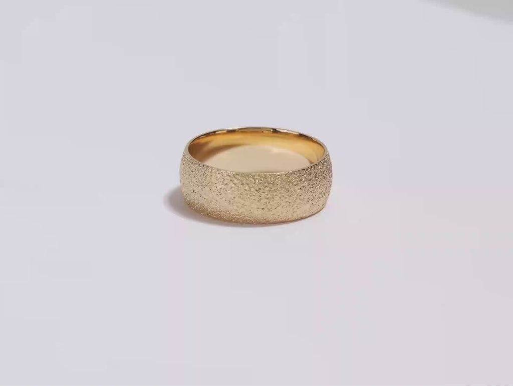A video showing a yellow gold 8mm domed stardust men's wedding band spinning on a white background