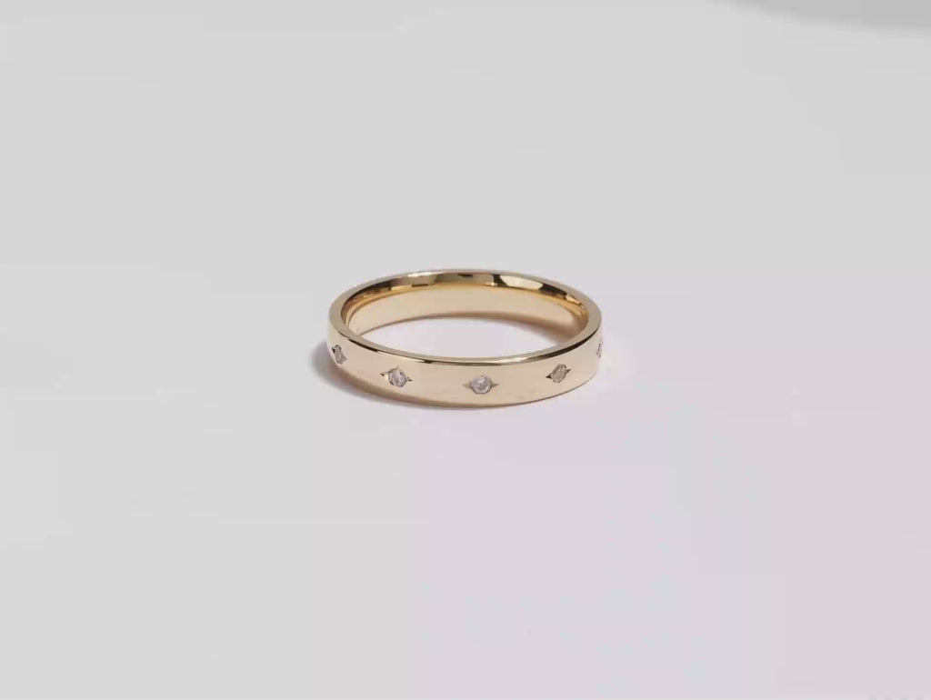 A video showing a yellow gold 4mm slit-bezel set eternity men's diamond wedding band spinning on a white background.