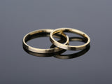 Two brushed gold wedding bands on reflective surface