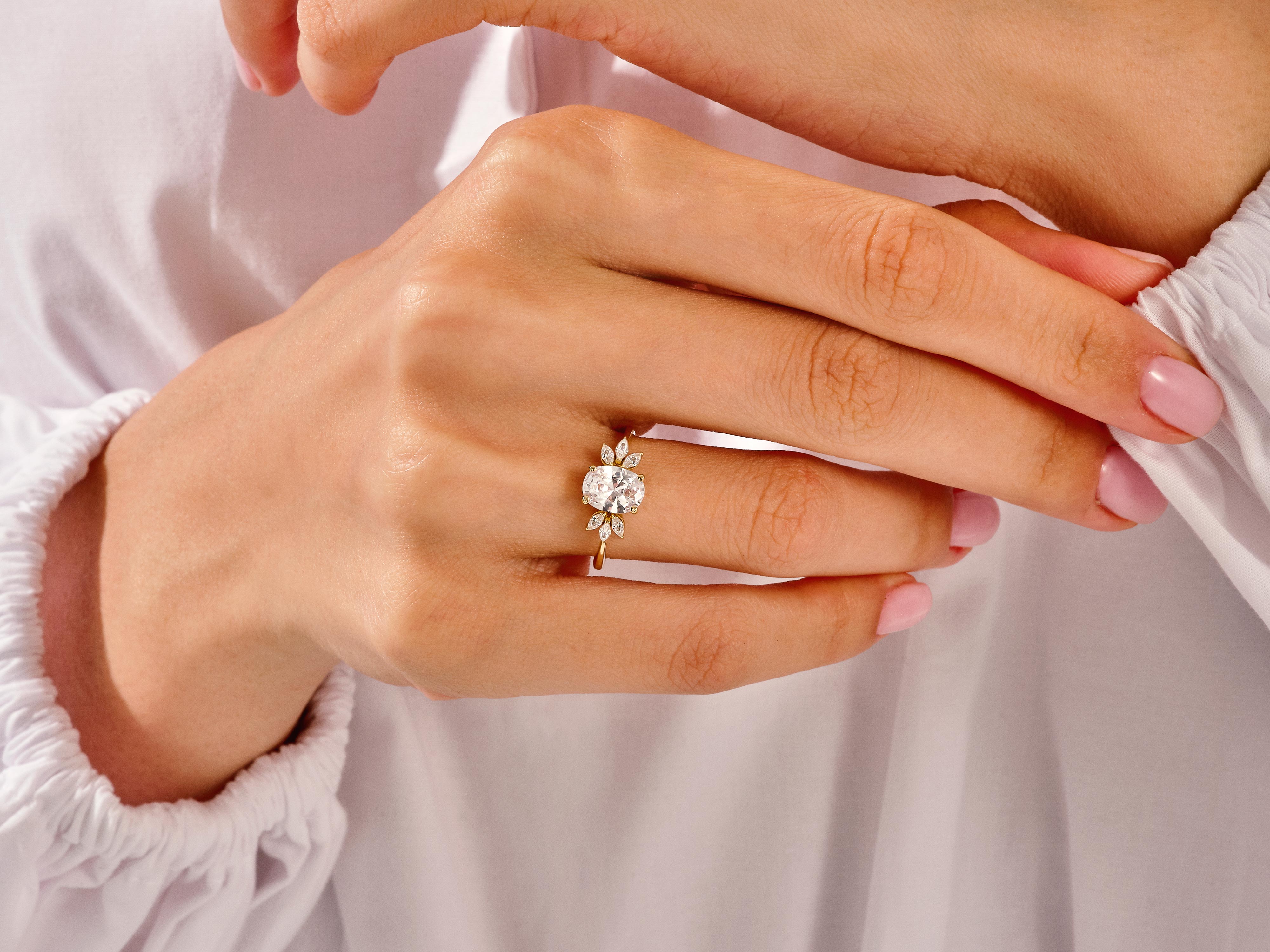 Oval diamond engagement ring with floral accents on a woman's hand