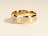 Gold wedding band with brushed finish and textured edges