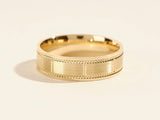 Gold wedding band with textured detail and beaded edges