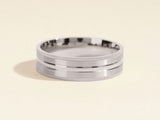 Silver band ring with textured edges and a polished center groove