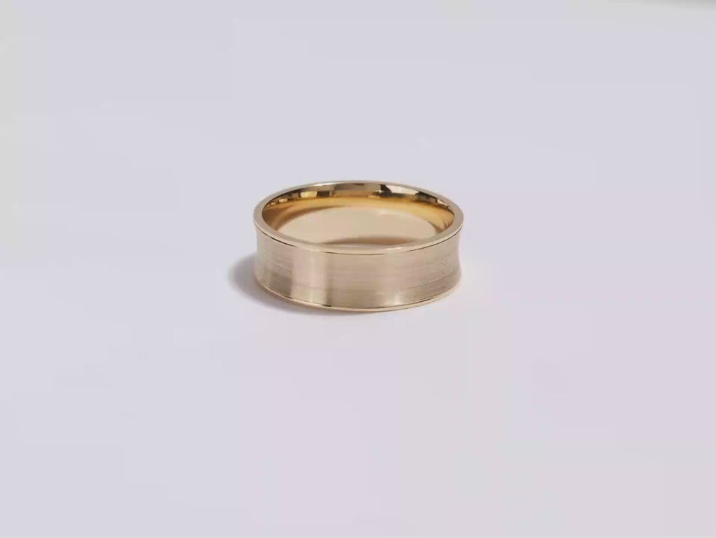 A video showing a yellow gold 7mm matte concave men's wedding band spinning on a white background.